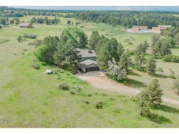 Expansive property featuring lush greenery, mature trees, and a charming home with a spacious driveway and attached garage at 9212 Tanglewood Rd, Franktown, CO 80116