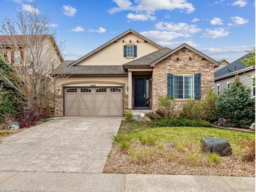 Charming home featuring a stone facade, well-manicured lawn, and attached two-car garage at 22310 E Chenango Dr, Aurora, CO 80015
