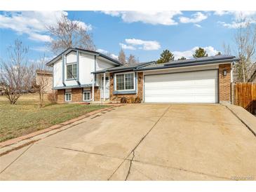 Charming home featuring brick accents, solar panels, an attached two-car garage, and a long concrete driveway at 9605 W David Ave, Littleton, CO 80128