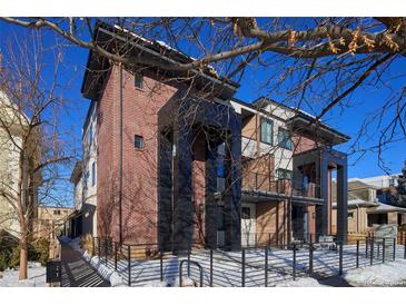 Stunning three-story townhome featuring brick and contemporary design with sleek black accents and a fenced yard at 25 S Washington St # 2, Denver, CO 80209