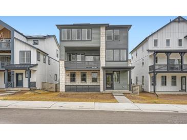 Modern two-story home with gray siding and stone accents, complemented by well-manicured landscaping at 7308 Waterleaf Trl, Littleton, CO 80125