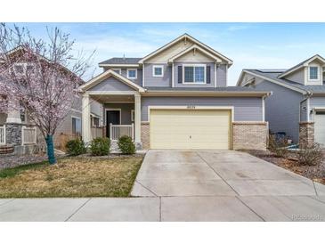 Charming two-story home featuring a two-car garage, well-maintained lawn, and inviting covered front porch at 18039 E 108Th Pl, Commerce City, CO 80022