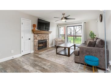 Cozy living room features a stone fireplace, a ceiling fan, and a sliding glass door to the balcony at 8666 Decatur St # 254, Westminster, CO 80031