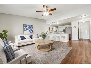 Open concept living room with white sofa, wooden table, and wood flooring at 795 S Alton Way # 5D, Denver, CO 80247