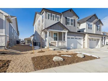 Two-story townhome with gray and white siding, two-car garage, and small front yard at 6575 N Nepal St, Aurora, CO 80019
