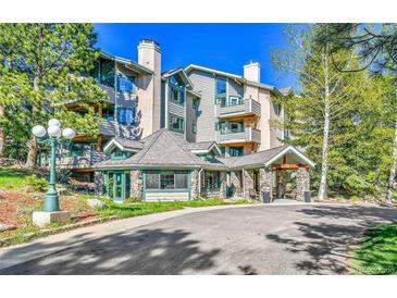 Inviting condo complex with stone accents and a covered entryway surrounded by lush landscaping at 31819 Rocky Village Dr # 418, Evergreen, CO 80439