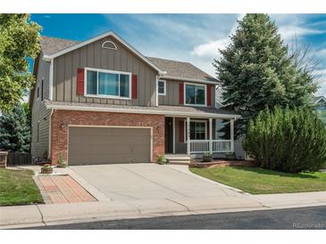 Charming two-story home with a brick and siding exterior, complemented by a well-maintained lawn and driveway at 14170 W Warren Dr, Lakewood, CO 80228