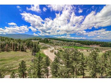 Scenic aerial view of wooded property with athletic fields and mountain views under a vibrant blue sky at 10550 Highway 73, Conifer, CO 80433