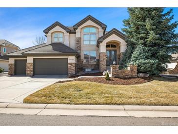 Beautiful two-story home with stone accents, manicured lawn, and a large attached two car garage at 10057 S Shadow Hill Dr, Lone Tree, CO 80124