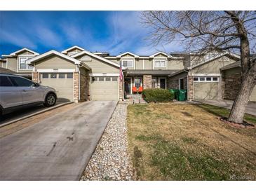 Charming townhome with stone accents, an attached garage, and well-maintained landscaping at 9267 Welby Rd Ter, Denver, CO 80229