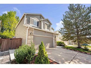 Charming two-story home features a well-manicured lawn and attached two-car garage, with tan siding and brick accents at 4857 Tarcoola Ln, Highlands Ranch, CO 80130