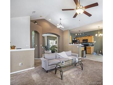 Open living room with carpet, ceiling fan, gray couch, and archway to other rooms at 12943 N Lafayette St # H, Thornton, CO 80241