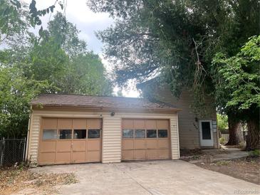 Two car garage with visible doors attached to the tan home at 1413 Centennial Dr, Longmont, CO 80501