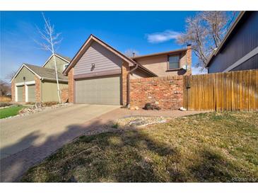 Cozy home featuring a two-car garage and a charming brick wall creating a private front yard space at 8737 Garrison Ct, Arvada, CO 80005