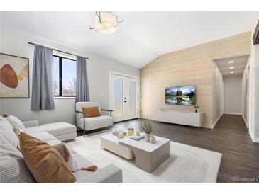 Bright living room features shiplap accent wall, modern furniture, and access to the outside through double doors at 8367 S Reed St # A3, Littleton, CO 80128