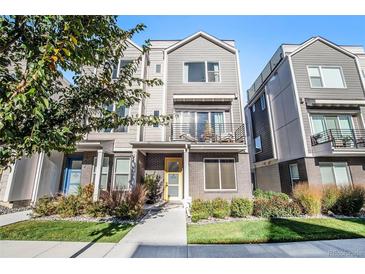 Attractive townhouse features a yellow front door, a small balcony and manicured landscaping at 888 S Valentia St # 101, Denver, CO 80247