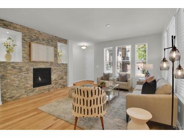 Bright living room featuring a stone fireplace, hardwood floors, and large windows at 5887 S Taft Ln, Littleton, CO 80127
