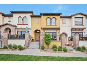 Charming townhome showcasing stucco facade, front patios, and beautifully landscaped front yard at 15592 W Wesley Ave, Lakewood, CO 80228