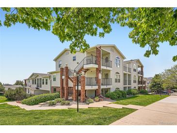 Exterior view of a well-maintained apartment building with brick accents, landscaping, and a clear blue sky at 1648 S Cole St # A2, Lakewood, CO 80228
