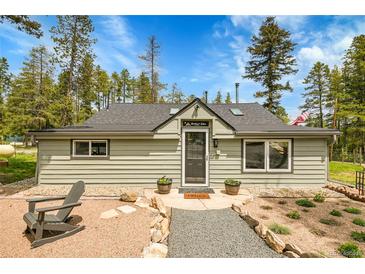 Charming home with a stone walkway, lush landscaping, and a relaxing chair on the front porch at 10887 Goodheart Ave, Conifer, CO 80433