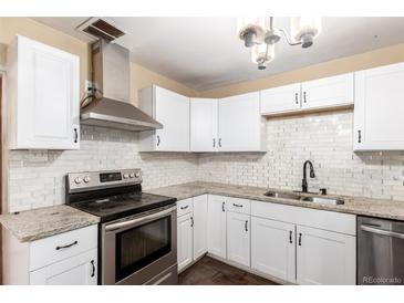 Bright kitchen featuring white cabinetry, subway tile backsplash, stainless steel appliances, and granite countertops at 1151 Revere St, Aurora, CO 80011
