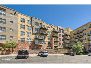 Multi-story condominium building with balconies, brick accents, and a parking lot in front on a sunny day at 9079 E Panorama Cir # 419, Englewood, CO 80112