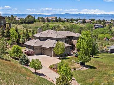 Stunning home featuring a stone facade, three-car garage, mature trees, and mountain views in a scenic neighborhood at 6995 S Ensenada St, Aurora, CO 80016