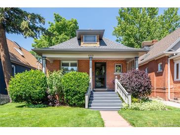 Charming brick home with covered front porch, landscaped lawn, and inviting curb appeal at 669 S Washington St, Denver, CO 80209