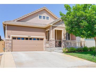 Inviting two-story home featuring a two-car garage, charming porch, and well-maintained lawn at 12513 Grape St, Thornton, CO 80241