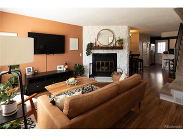 Inviting living room featuring a brick fireplace, hardwood floors, and stylish decor at 19738 Applewood Ct, Parker, CO 80138