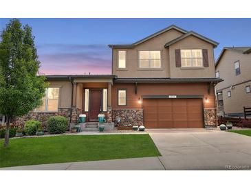 Two-story home with a brown garage door, stone accents, and a well-manicured lawn at 436 Sage Grouse Cir, Castle Rock, CO 80109
