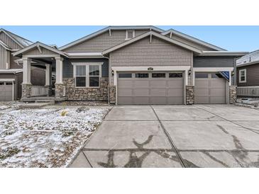 Charming home featuring stone accents, a three-car garage, and a well-maintained yard on a partially snowy day at 3877 Treadway Pt, Castle Rock, CO 80108