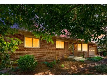 Charming brick home with front yard landscaping and warm interior lighting glowing through the windows at 2698 S Niagara St, Denver, CO 80224