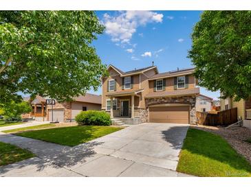 Charming two-story home with a well-manicured lawn, stone accents, and an attached two-car garage at 16643 E 101St Ave, Commerce City, CO 80022