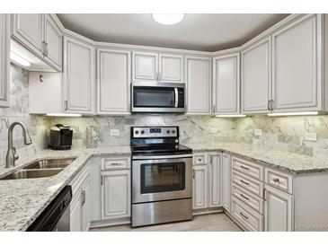 Well-lit kitchen with granite countertops, stainless steel appliances, and white cabinets at 795 S Alton Way # 4C, Denver, CO 80247