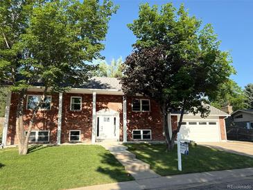 Charming brick home boasts lush landscaping, a pristine lawn, and a welcoming two-car garage at 6842 Garland St, Arvada, CO 80004