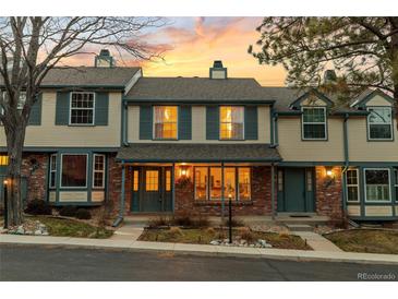 Charming townhome with brick facade and inviting covered porch beneath a beautiful sunset sky at 7068 E Briarwood Dr, Centennial, CO 80112