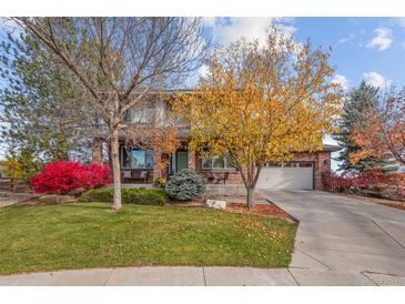 Charming two-story home with a brick facade, well-manicured lawn, mature trees, and a cozy front porch at 4495 Rainbow Ln, Broomfield, CO 80020