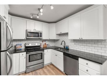 Well-lit kitchen features stainless steel appliances, granite countertops, white cabinets, and subway tile backsplash at 6940 E Girard Ave # 210, Denver, CO 80224