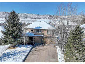 Stunning two-story home with a three-car garage and snow-covered roof, set against a beautiful mountain backdrop at 10914 W Coco Pl, Littleton, CO 80127