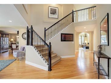 Spacious foyer with hardwood floors, staircase with iron railings, and soaring ceilings at 10914 W Coco Pl, Littleton, CO 80127