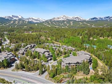 Scenic aerial view of a mountain community nestled amongst evergreen trees with snow-capped mountains in the background at 50 Mountain Thunder Dr # 1402, Breckenridge, CO 80424