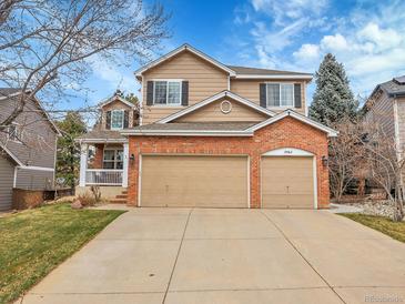 Two-story home featuring brick accents, a three-car garage, and a well-maintained lawn at 10062 Eagle Valley Way, Highlands Ranch, CO 80129