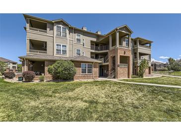 Multi-level condo building shows manicured lawn, brick accents, and upper level balconies at 12818 Ironstone Way # 101, Parker, CO 80134