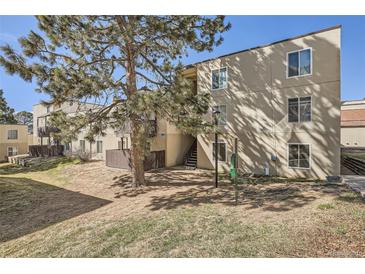 A tan three-story apartment building with stairs and a large tree in the front at 9995 E Harvard Ave # 246, Denver, CO 80231