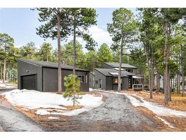 Exterior view of a modern home with a detached garage, surrounded by trees and some snow on the ground at 19185 Shadowood Dr, Monument, CO 80132