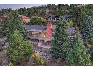 Secluded home with a brick chimney and a deck surrounded by lush trees and greenery at 345 Scrub Oak Way, Monument, CO 80132
