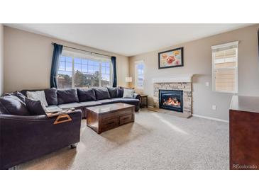 Cozy living room with a stone fireplace, large window, and comfortable seating at 10294 E Telluride Ct, Commerce City, CO 80022
