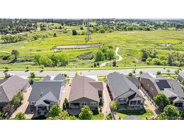 Stunning aerial view of houses with lush green space, trails, and distant windmill at 24028 E Caleb Pl, Aurora, CO 80016