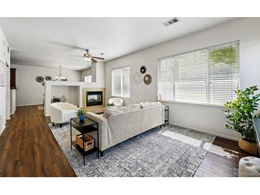Bright living room featuring a fireplace, ceiling fan, hardwood flooring and modern decor at 13020 Grant W Cir # A, Thornton, CO 80241